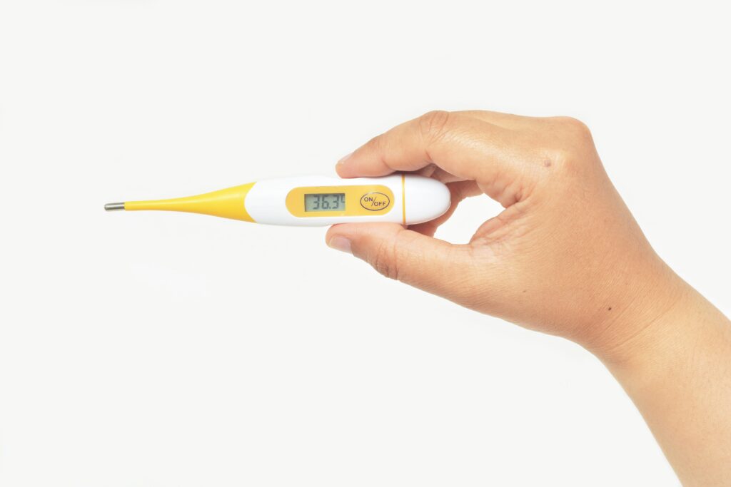 Eine Hand hält ein Fieberthermometer.