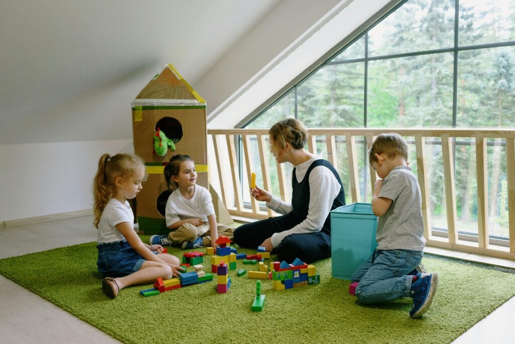 Kindergärtnerin spielt mit Kindern.