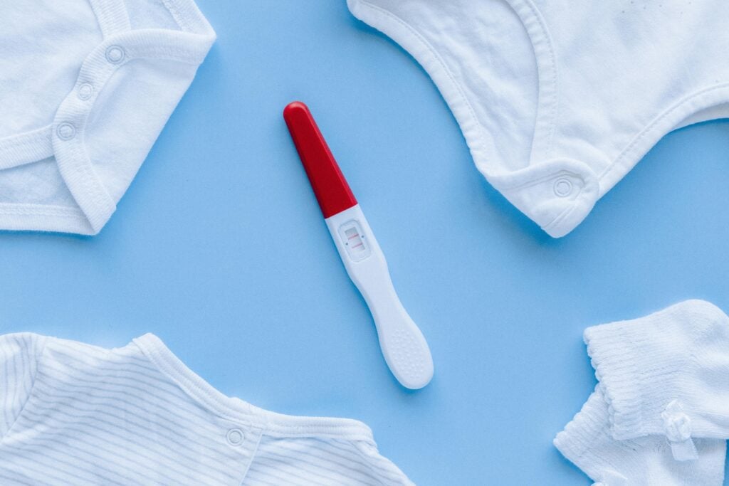 Ein Schwangerschaftstest und Baby-Kleidung.
